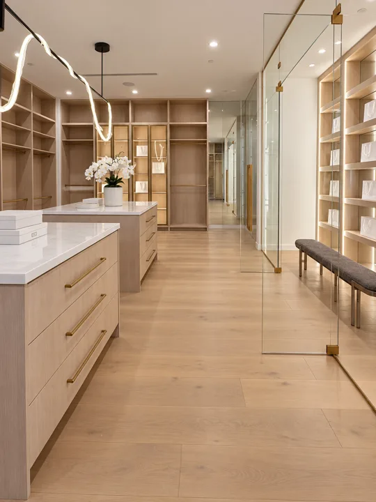 Walk-in closet with pale oak cabinetry and a center island