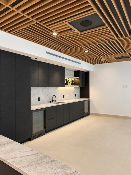 Dark wet bar beneath a slatted wood ceiling