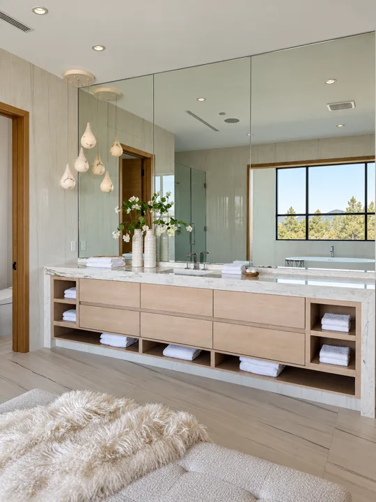 Long oak double vanity with pendant lights and stone counters