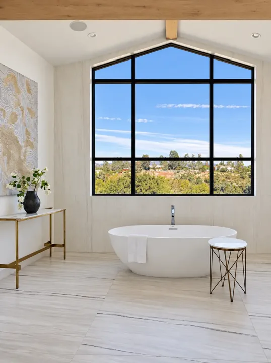 Freestanding bathtub beneath a large picture window