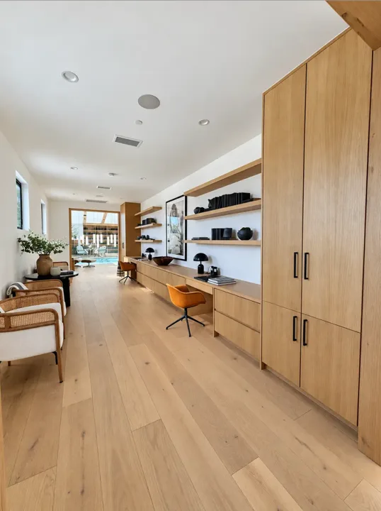 Open living space with oak cabinetry and white display shelves