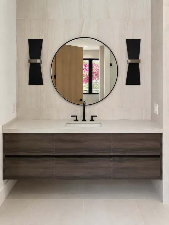Round mirror above a dark wood vanity