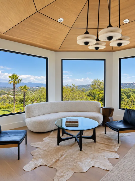 Curved sofa beside panoramic windows and a wood ceiling