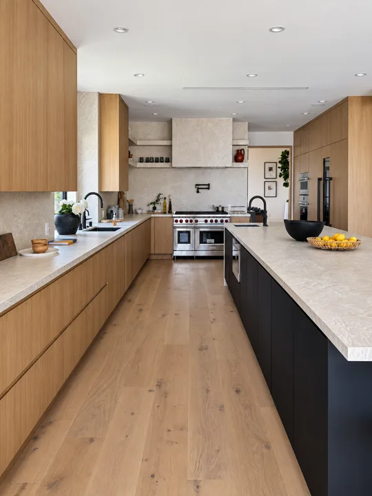 Oak kitchen cabinetry beside a dark stone island