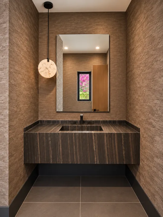 Dark stone vanity with a pendant light and textured walls