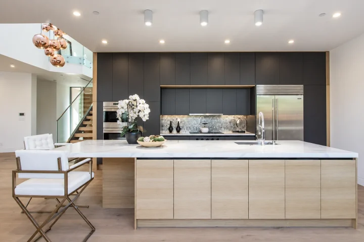 Light oak kitchen island with a white stone countertop, dark full-height cabinetry and stainless steel appliances