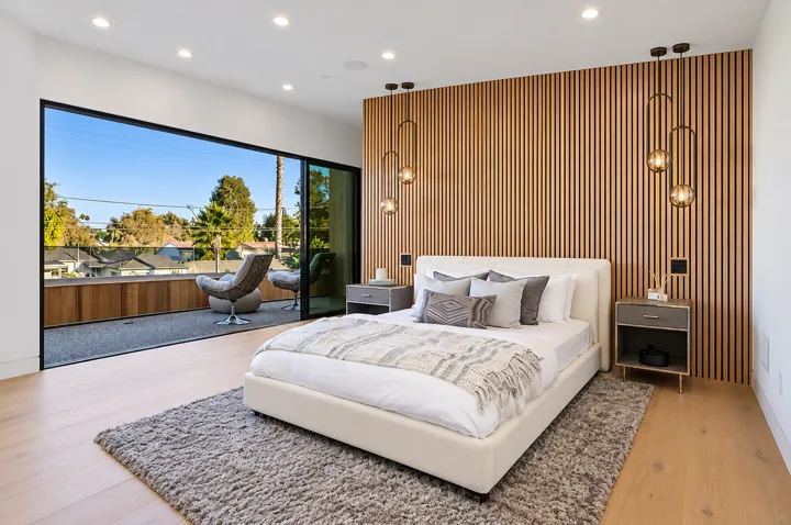 Bedroom with a slatted wood wall and brass pendant lights