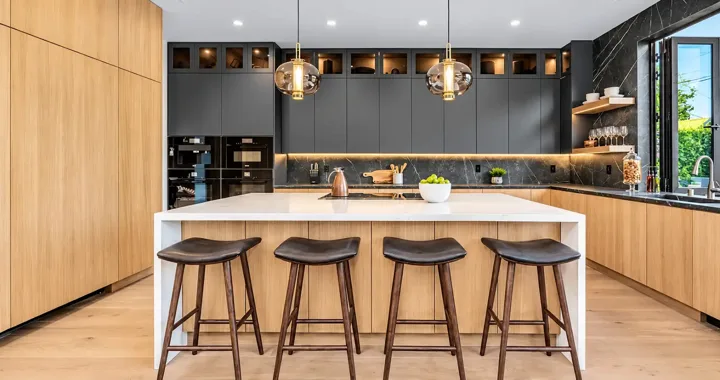 Dark kitchen cabinetry with oak island storage and brass pendants