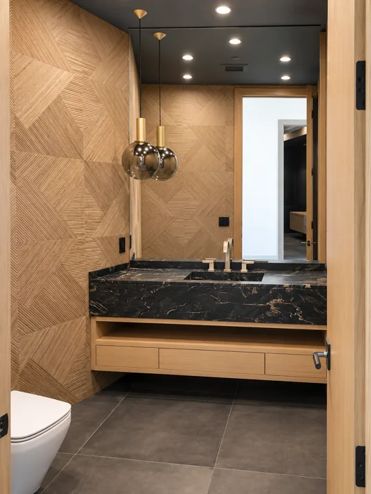 Dark stone sink against a herringbone wood feature wall
