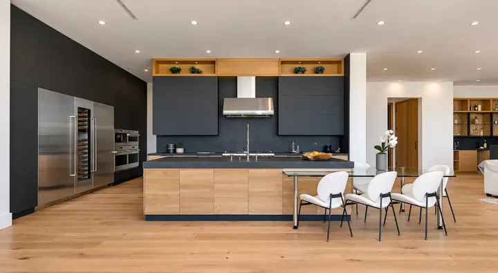 Dark kitchen cabinets above an oak island with a black countertop