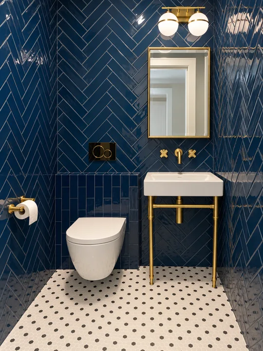 Blue herringbone bathroom tile with brass fixtures