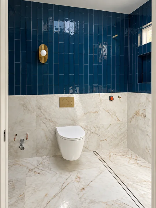 Walk-in shower with deep blue tile above marble walls