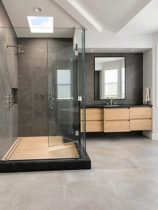 Bathroom with an oak vanity and dark gray tiled walls