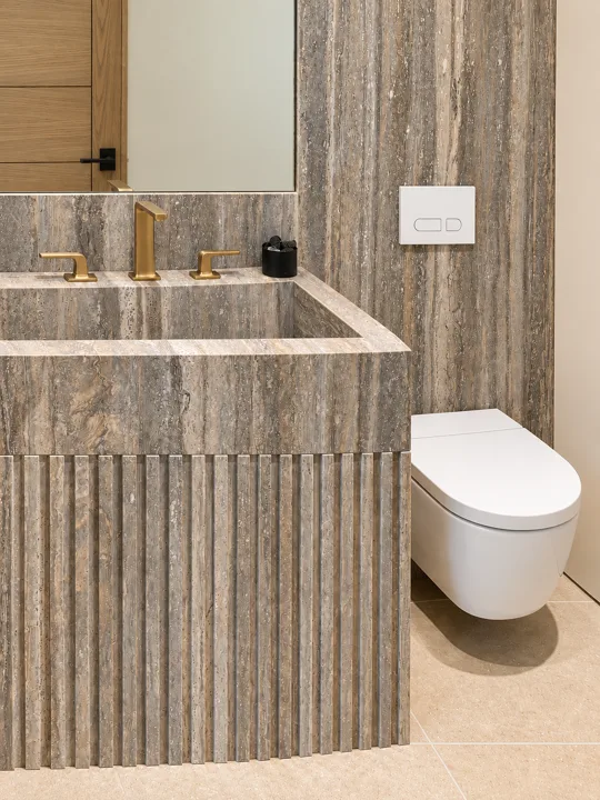 Textured stone vanity with brass fixtures