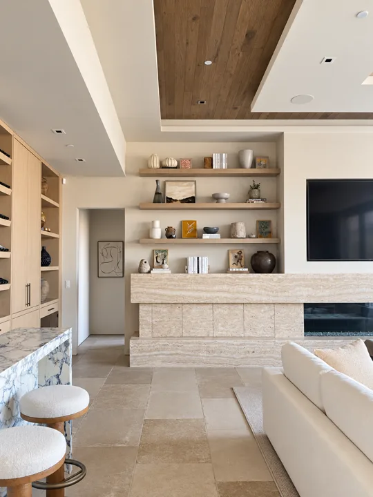 Living room with a pale stone fireplace and wood display shelves