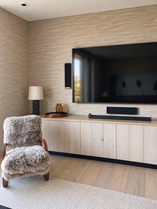 Low oak media cabinetry against a textured wall