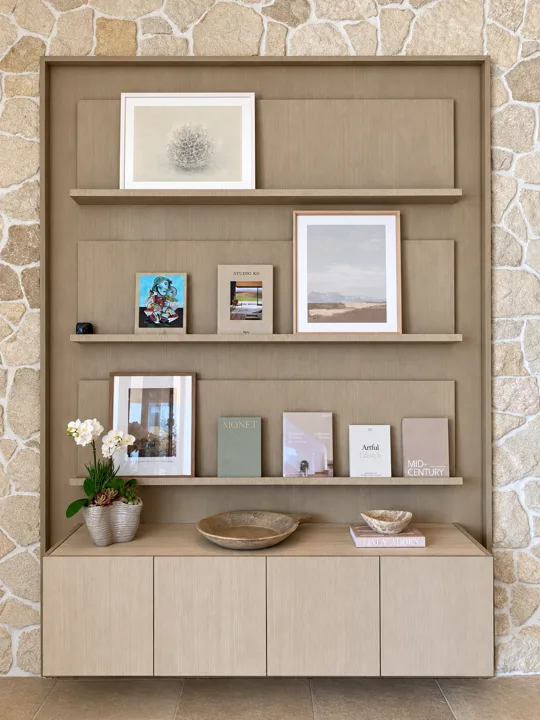 Oak display shelves with framed artwork and books, set into a pale stone wall
