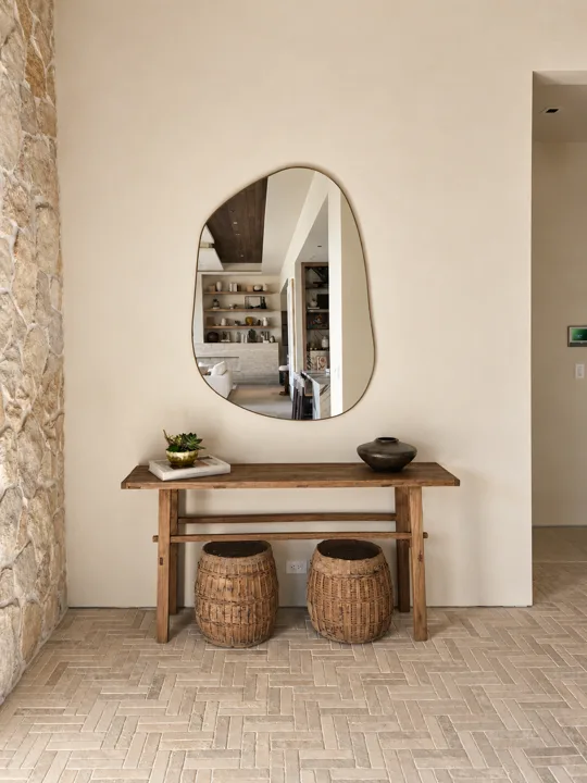 Entry console with a round mirror beside textured stone