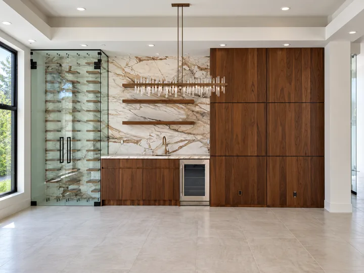 Oak bar cabinetry with a marble backsplash and glass-front wine room