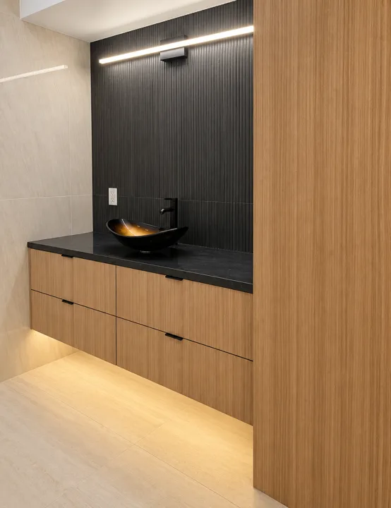 Oak bathroom vanity with a brass bowl sink and dark ribbed wall