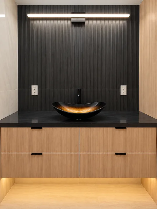 Brass vessel basin on a dark counter above oak cabinetry