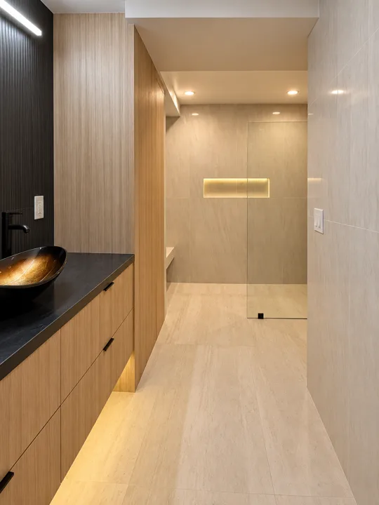 Oak bathroom cabinetry beside a stone walk-in shower